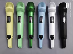 five different colored microphones lined up in a row on a gray surface with the same color