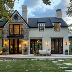 a large white house with black windows and lights on it's front door is lit up at night