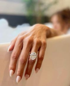 a close up of a person's hand with a diamond ring on their finger