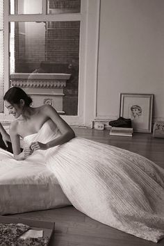 a woman sitting on top of a bed in a room with a large white dress