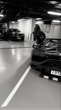 two black sports cars parked in a parking garage next to each other on the floor