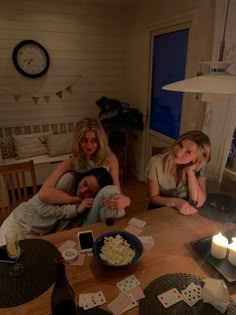 two women sitting at a table with playing cards and candles on the table in front of them