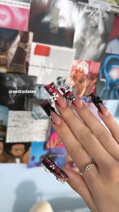 a woman's hand with black and pink nail polish holding up her manies