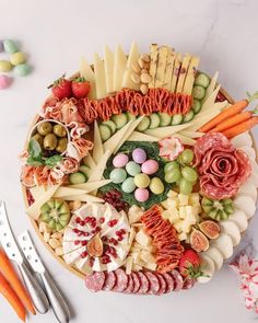 a platter filled with different types of cheese and meats next to utensils