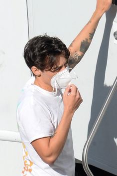 a man wearing a face mask is washing his hands on the side of a boat