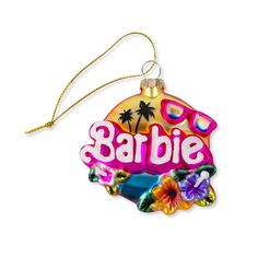 a glass ornament with the word barbie on it and palm trees in the background