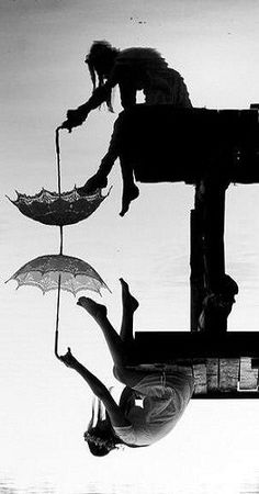 two people hanging upside down from umbrellas in the air over water at sunset or dawn