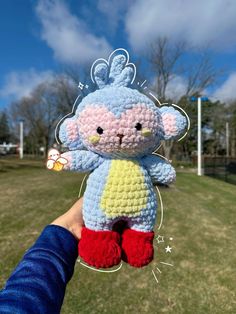 a hand holding up a crocheted stuffed animal