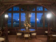 a dining room table and chairs in front of a large window with lights on it