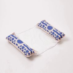 a blue and white pillow sitting on top of a piece of cloth next to a roll of toilet paper