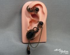 Wire wrapped gothic ear wrap with black onyx stones and chain, no piercing required. It's made of bronze artistic wire, antiqued brass chain, seed beads, an antiqued brass bezel, black onyx beads and cabochon, and a matching black glass briolette bead. One of a kind. For the left ear. You can find more ear wraps here: https://www.etsy.com/shop/bodaszilvia?section_id=10953132&ref=shopsection_leftnav_4 Plz, read my policies before buying. Thank you! If you are interested in news, work in progress Ear Wraps, Felt Pouch, Artistic Wire, Wrap Earrings, Black Onyx Stone, Onyx Bead, Jewelry For Her, Onyx Stone, Gothic Jewelry