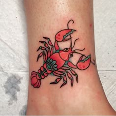 a small crab tattoo on the ankle with red flowers and green leaves around its claws