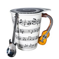 a coffee cup with musical notes on it and a guitar in the mug next to it