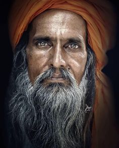 an old man with a long beard and orange turban is looking at the camera