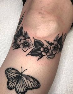 a black and white butterfly tattoo on the arm with flowers around it's wings