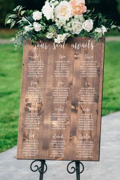 a wooden sign with flowers on it that says your seat awaits and the table numbers are