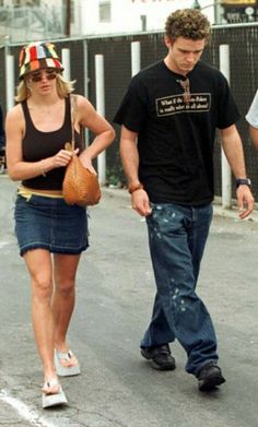 a man and woman walking down the street with one carrying a handbag in her other hand