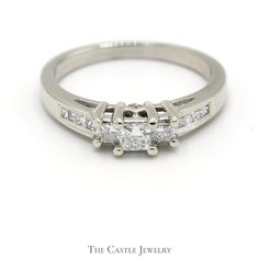 a three stone diamond ring with channeled shoulders and side stones in white gold or pallads