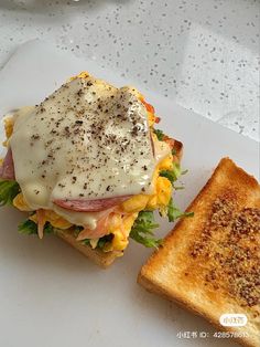 a sandwich with meat, cheese and lettuce on it next to a toasted piece of bread