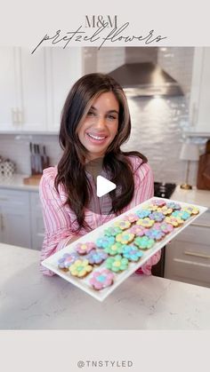 a woman is holding a tray of cookies