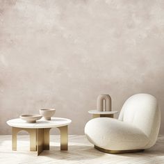 a white chair sitting next to a table on top of a hard wood floor in front of a gray wall