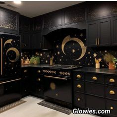 a kitchen with black cabinets and gold stars painted on the backsplash, along with potted plants