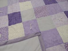 a purple and white patchwork quilt on a bed with the edge torn off from it