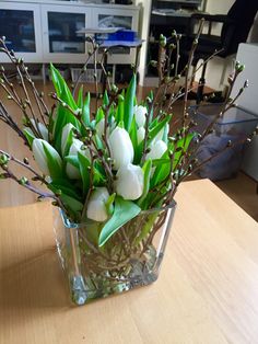 a vase filled with white flowers on top of a wooden table