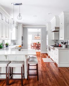 a large kitchen with white cabinets and wooden flooring, along with an island in the middle