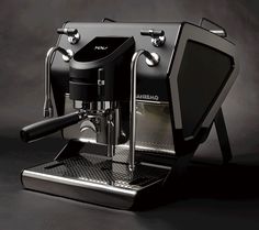 an espresso machine sitting on top of a black table next to a cup