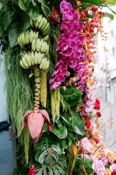 a bunch of flowers that are next to each other on a pole in front of a building