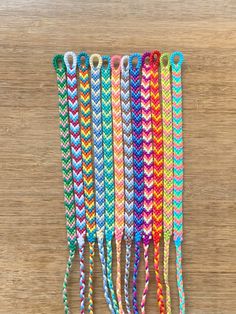 five different colored braided bracelets on top of a wooden table