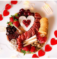 a heart shaped platter filled with meats, cheeses, fruit and crackers