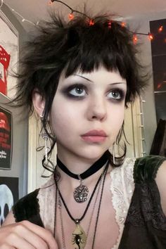 a woman with black hair and blue eyes is posing for the camera while wearing some necklaces