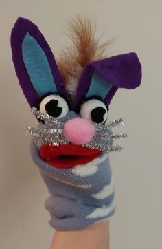 a hand with a puppet like animal wearing a blue and white striped sweater, silver sequins on it's wrist