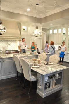 a group of people standing around a kitchen island