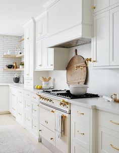 a kitchen with white cabinets and gold handles