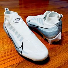 a pair of white nike soccer cleats sitting on top of a wooden floor