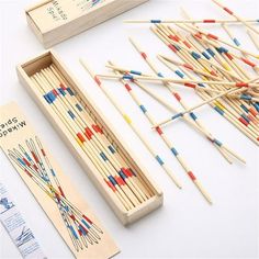 an assortment of knitting needles in a wooden box next to a ruler and needle tips