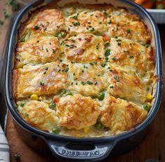 a casserole dish with chicken and vegetables in it on a wooden table next to other dishes