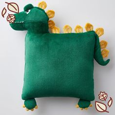 a green pillow with yellow flowers on the side and a stuffed animal in the middle