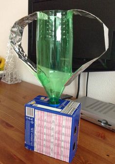 a green glass vase sitting on top of a cardboard box next to a computer monitor