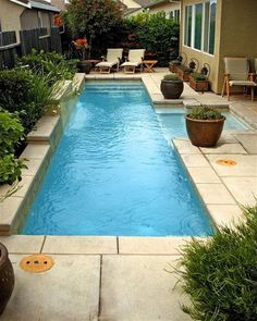 a small swimming pool in the middle of a yard with chairs and plants around it