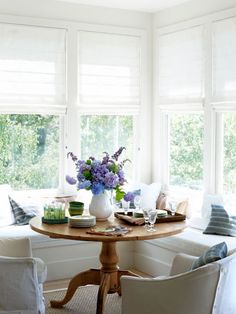 a table with flowers in a vase on top of it next to two white chairs