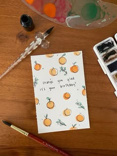 a card with oranges on it next to some watercolor paints