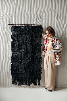 a woman standing next to a black piece of art