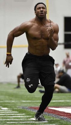 a shirtless man running on a football field