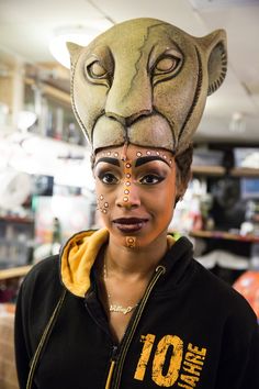 a woman wearing a lion mask and gold nose ring, in a store with other items on the shelves