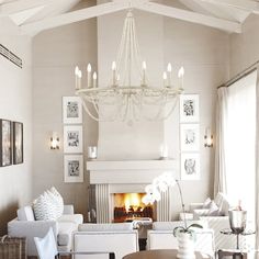 a living room filled with white furniture and a chandelier hanging from the ceiling