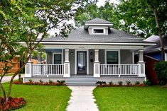 a gray house with white trim and porches